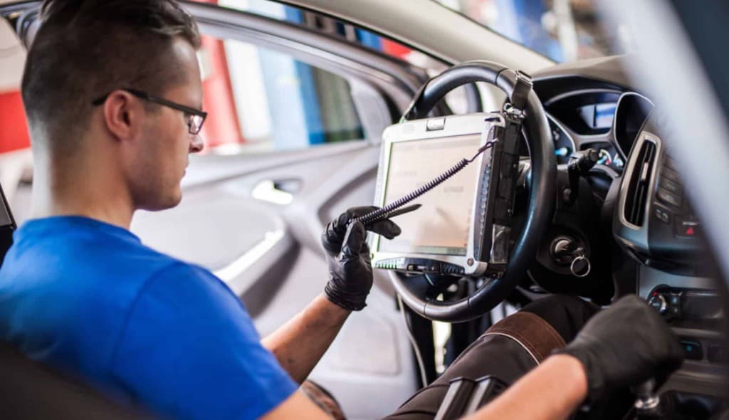 Technician performing diagnostic ADAS camera calibration with a tablet — Summit Auto Glass